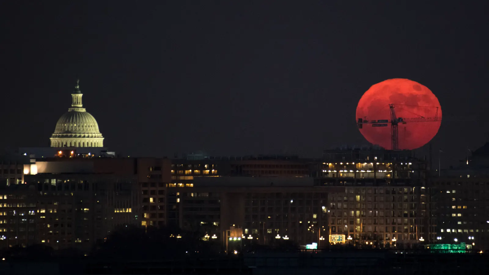 An orange full Moon rising behind a crane beside the U.S. Capitol dome in Washington on December 3, 2017, the first of three consecutive supermoons