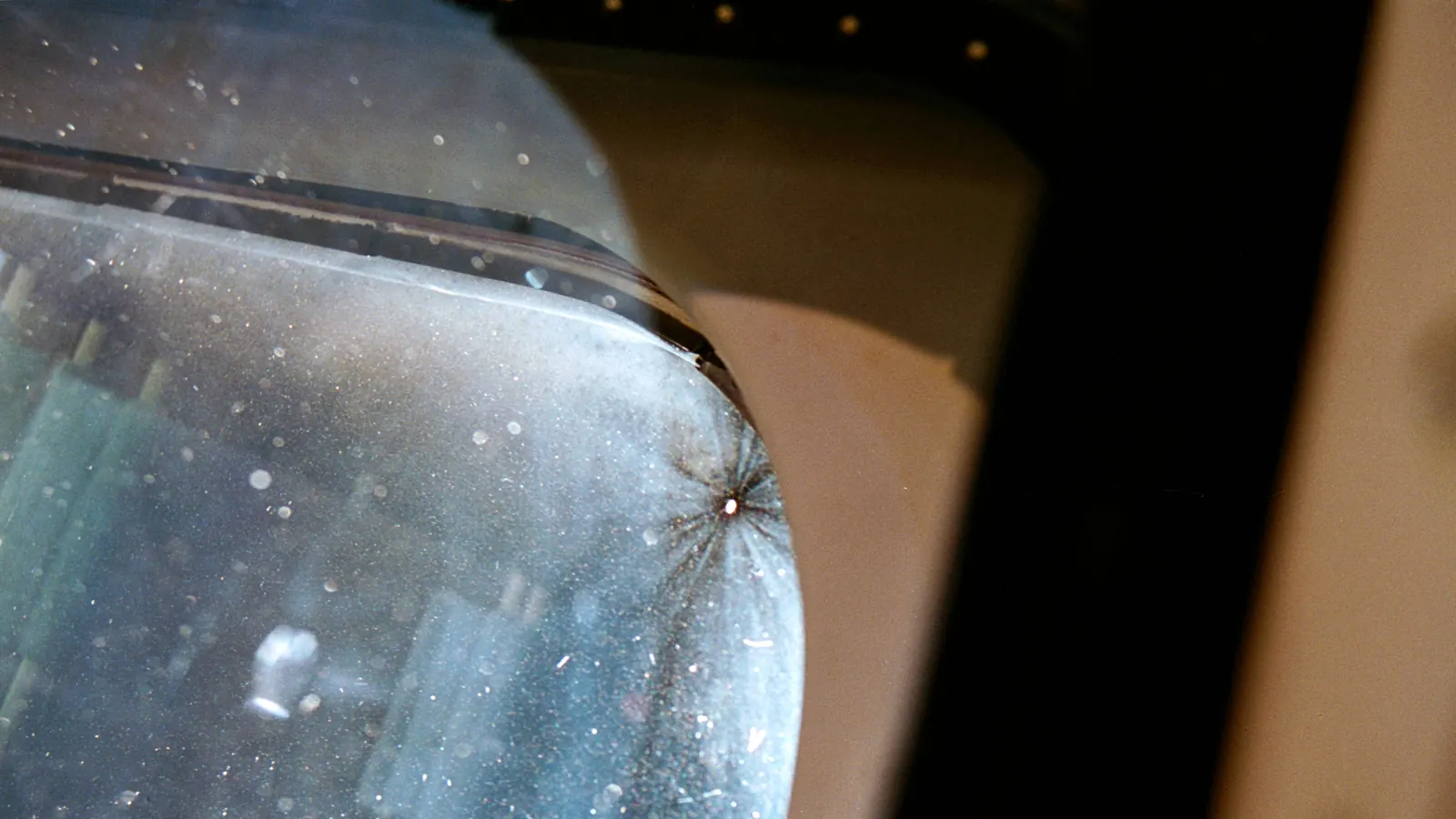 A small impact pit, about 1/16 inch across, in window 6 of the space shuttle Discovery during the STS-70 mission in July 1995, apparently from a piece of debris