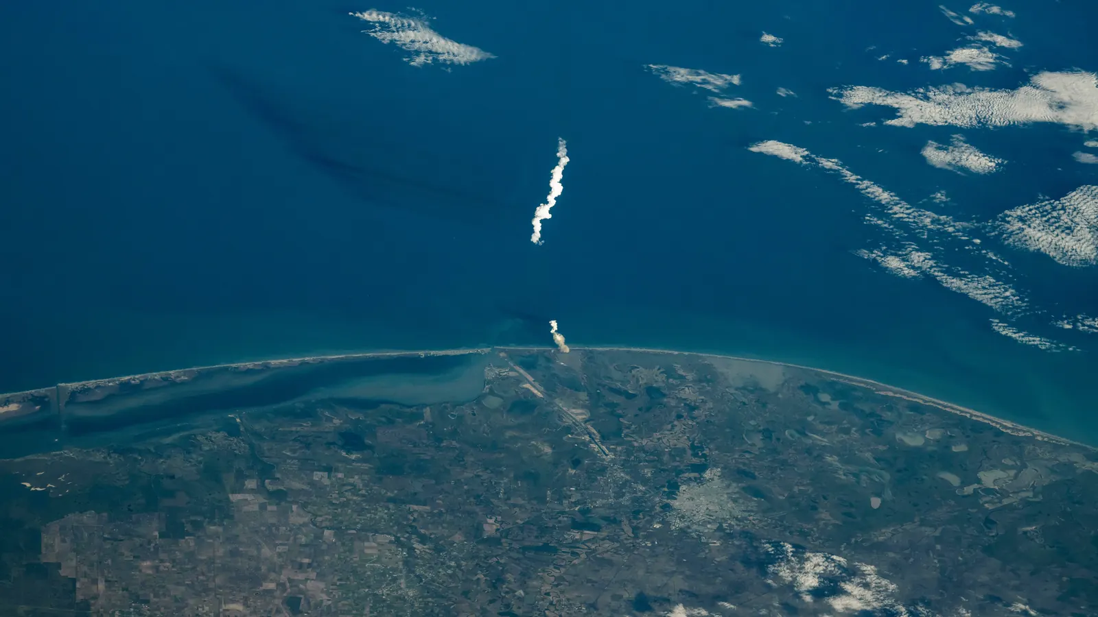 The white exhaust plume of SpaceX's sixth Starship test flight rising over the deep blue Gulf of Mexico from the South Texas coast, seen from the International Space Station on November 19, 2024