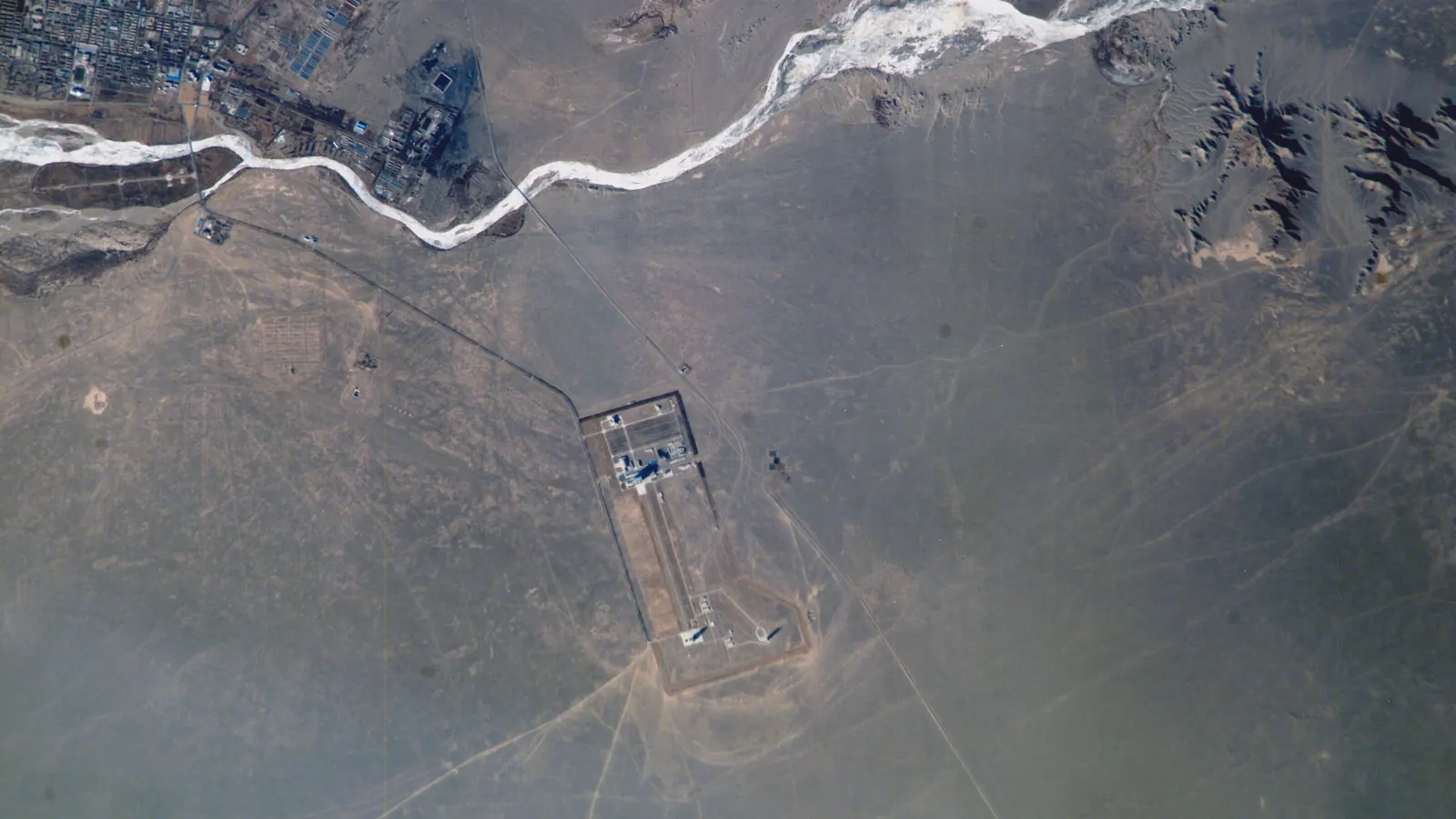 A launch complex at China's Jiuquan Satellite Launch Center in the desert of northern China, beside a braided river, photographed from the International Space Station in January 2005