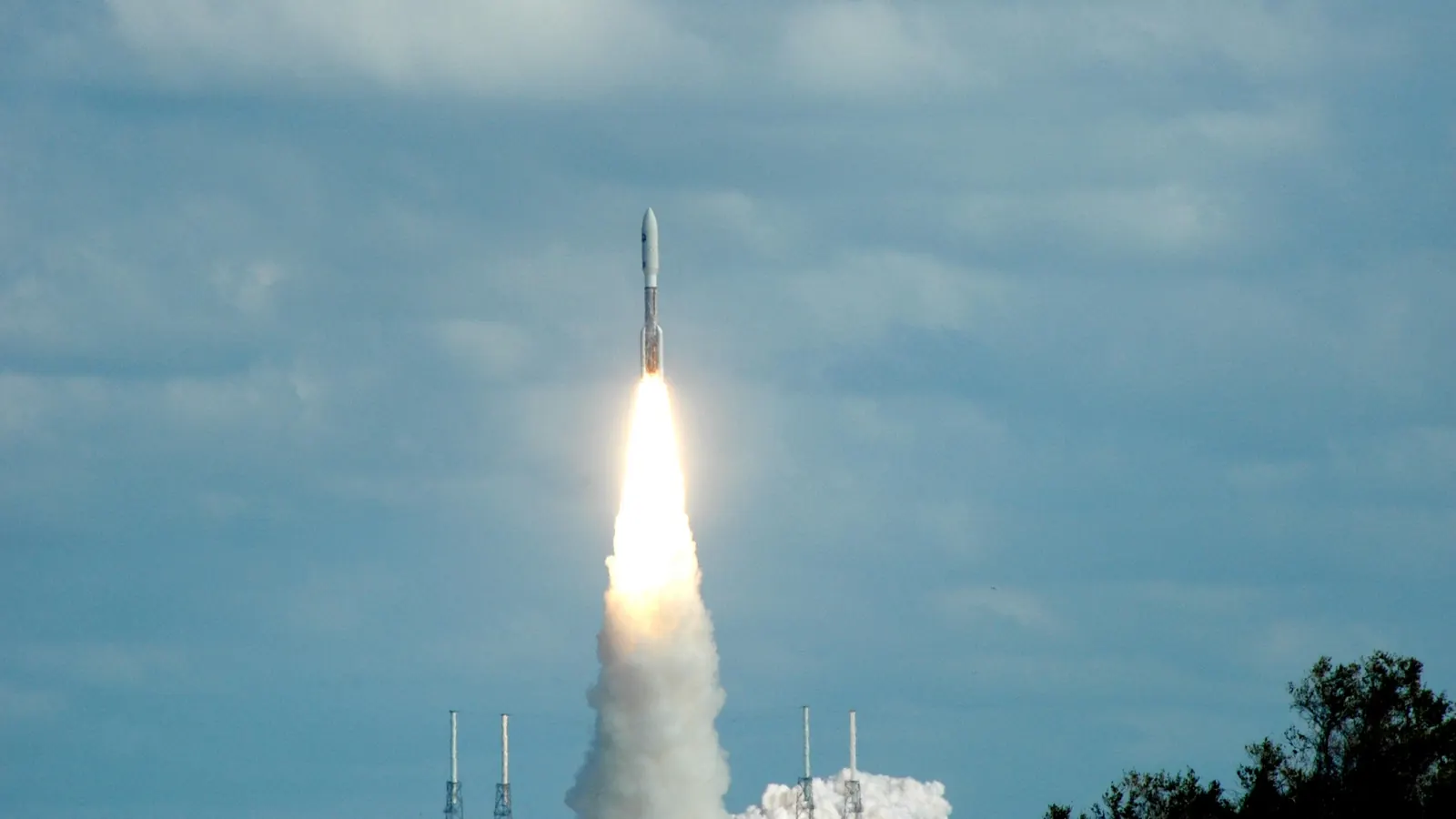 An Atlas V rocket climbing into a blue, cloud-scattered sky from Cape Canaveral on January 19, 2006, carrying NASA's New Horizons spacecraft